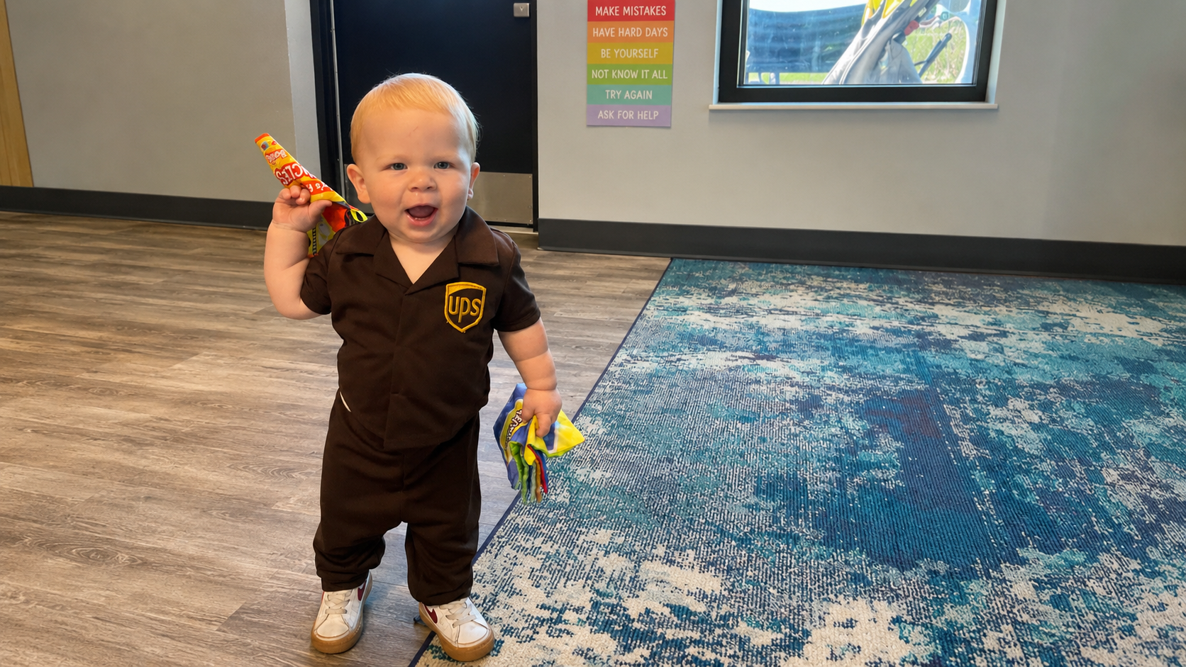 Toddler in a UPS costume smiling in a bright classroom
