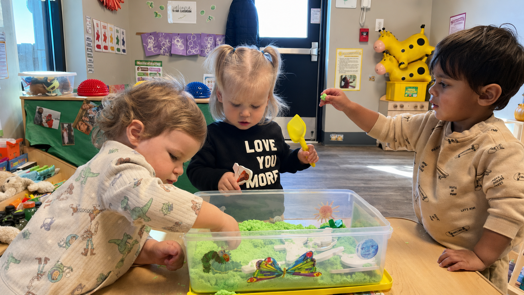 Toddlers exploring a hands-on sensory activity together at KinderKids Learning Center