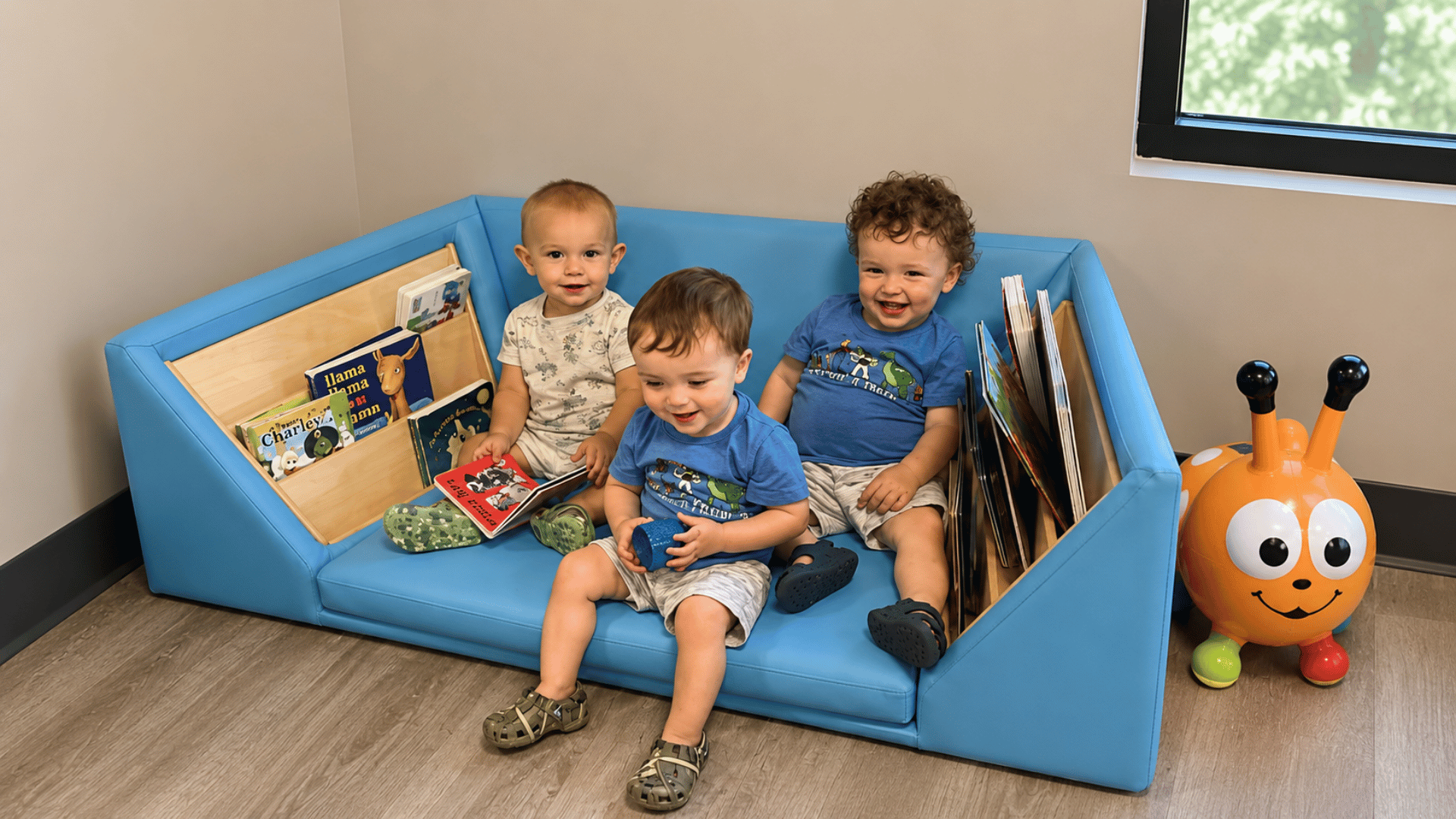 Toddlers reading together on a cozy classroom couch at KinderKids Learning Center