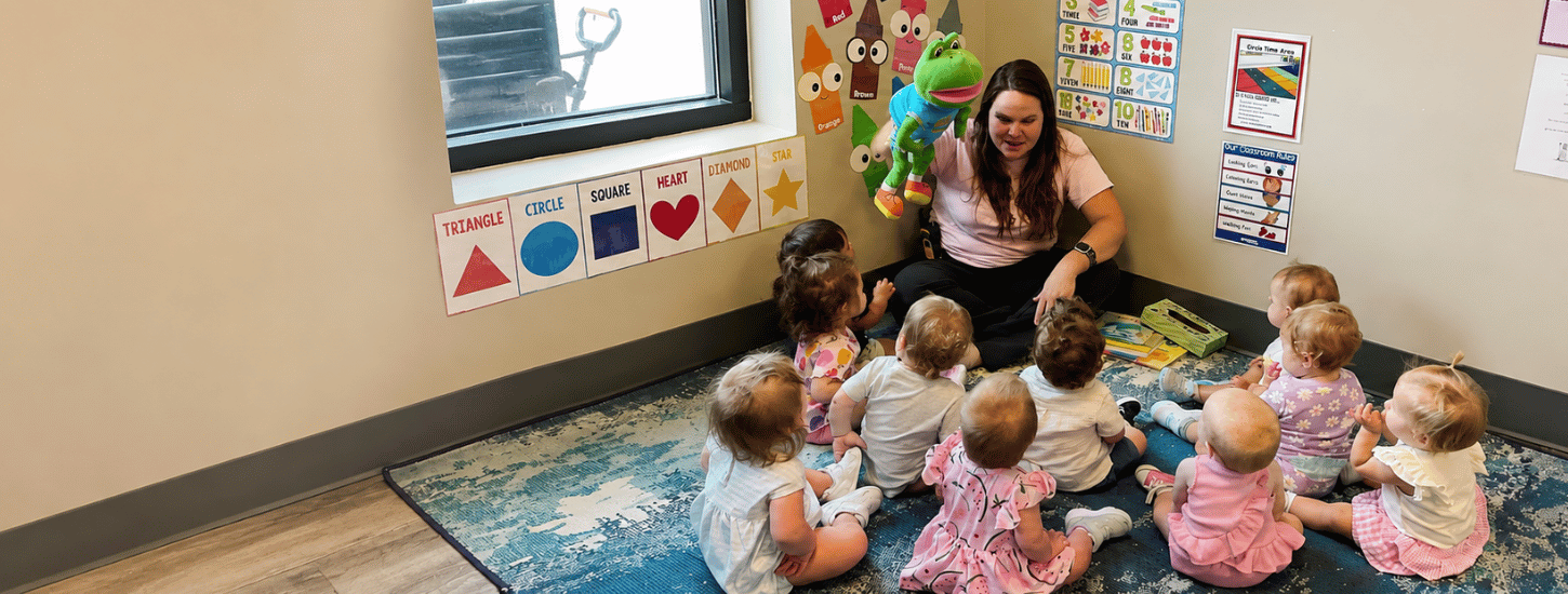 A teacher reading with infants during circle time at KinderKids Learning Center