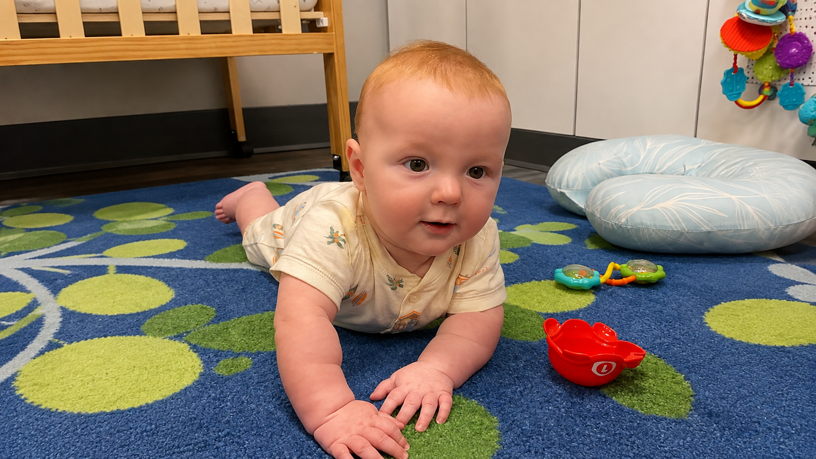 Baby on their tummy during tummy time in the bright KinderKids nursery